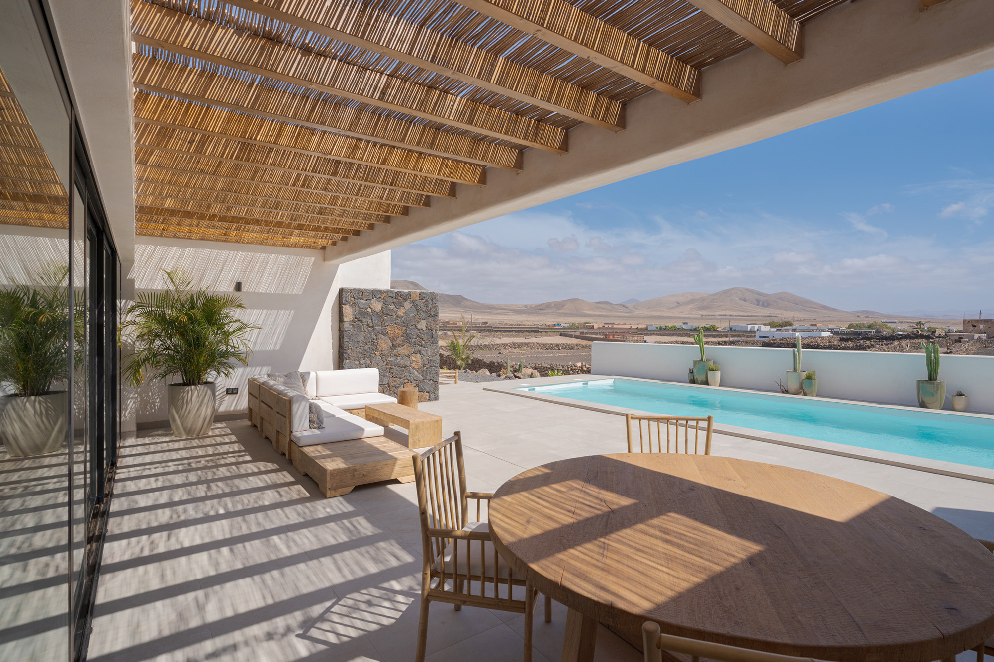 Covered terrace with lounge furniture overlooking pool and landscape